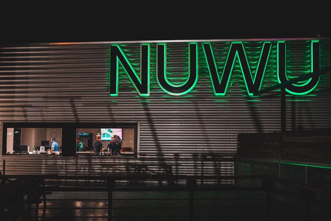 Lights on the outside of a building say "NUWU", this is the outside of the Sky High Lounge