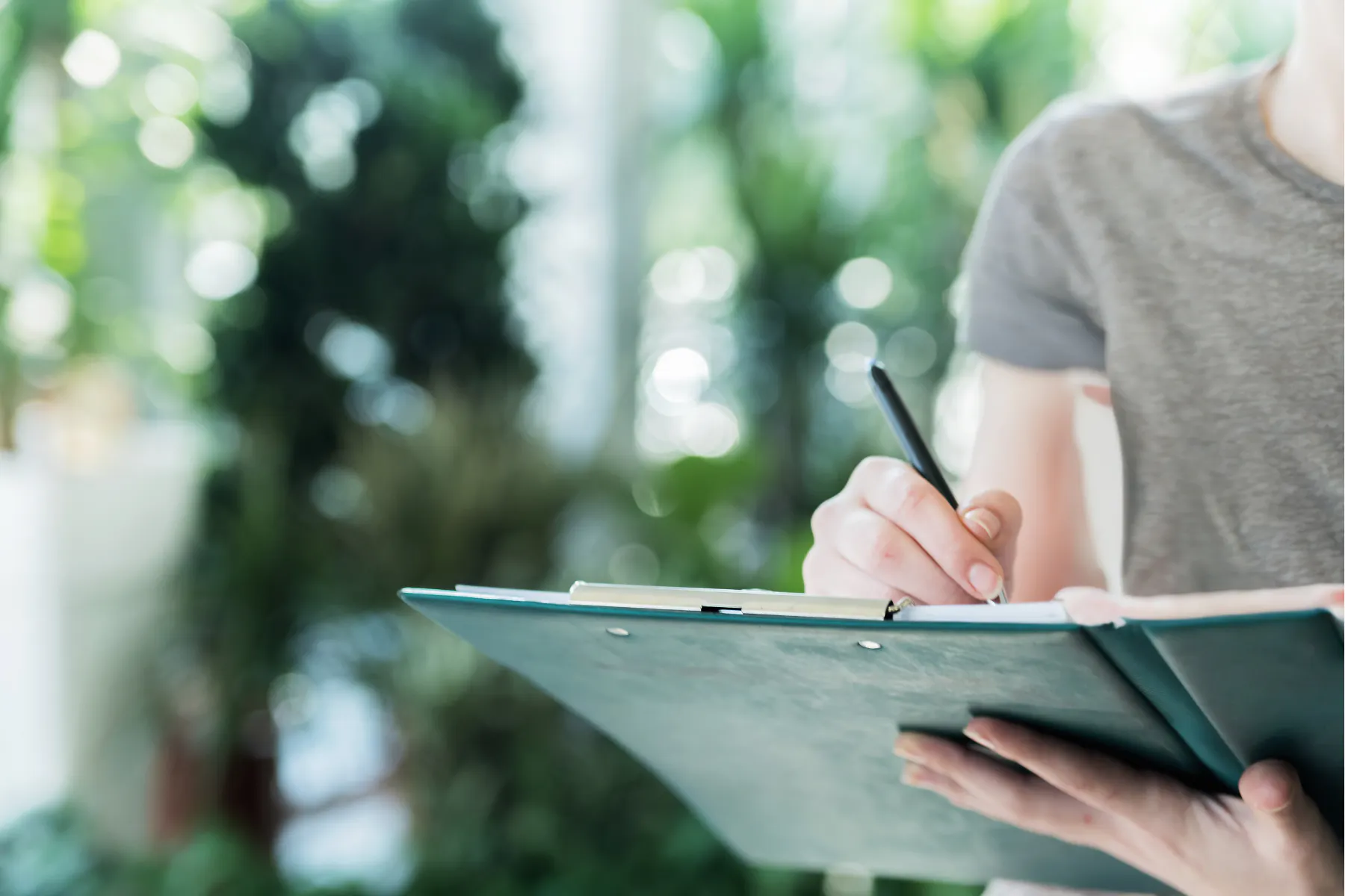 A person holds a binder with a checklist on it, and checks off opening and closing duties for their cannabis business