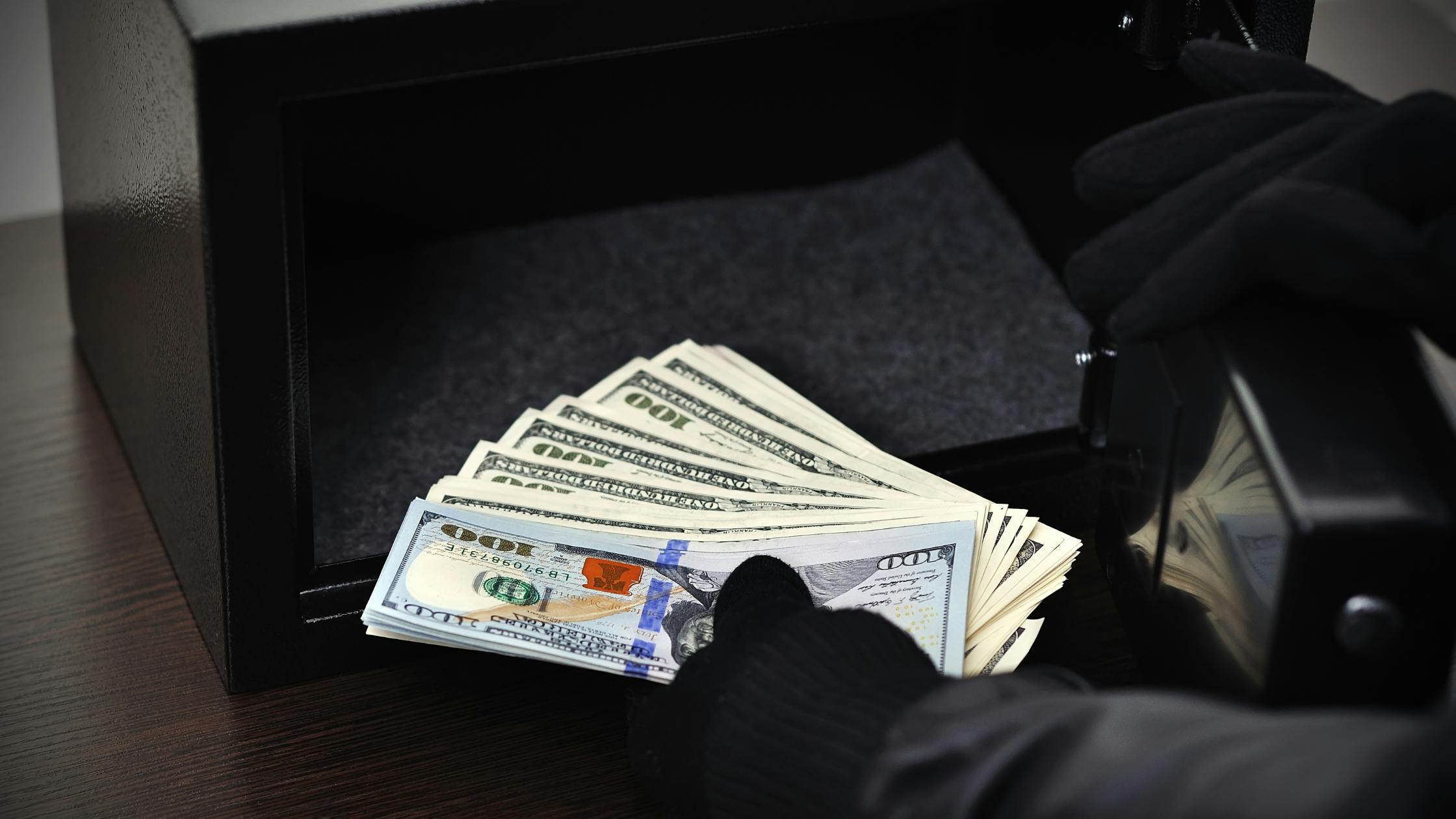 A hand holds thousands of dollars in cash, in denominations of 100s