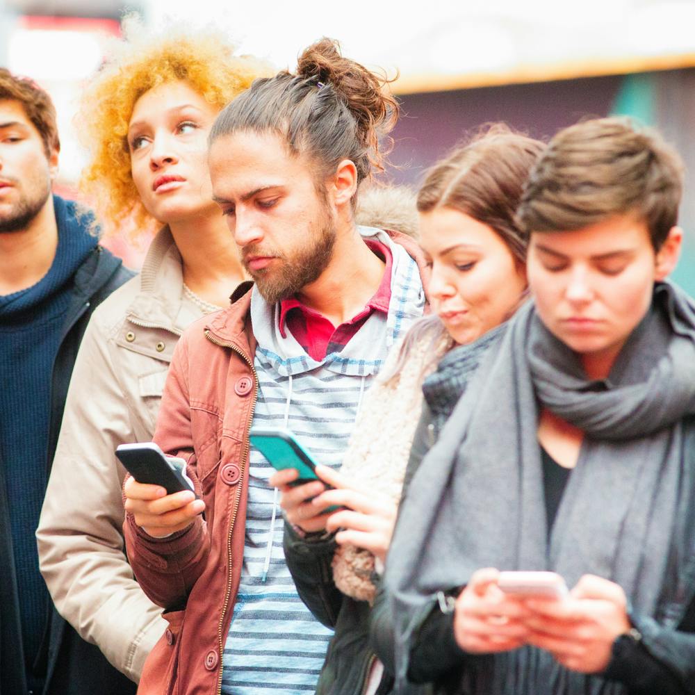 Inpatient young adults wait in the line for a dispensary. They seem frustrated and looking at their phones.