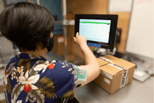 A worker unpacks an order and performs inventory management in the back room of a cannabis dispensary