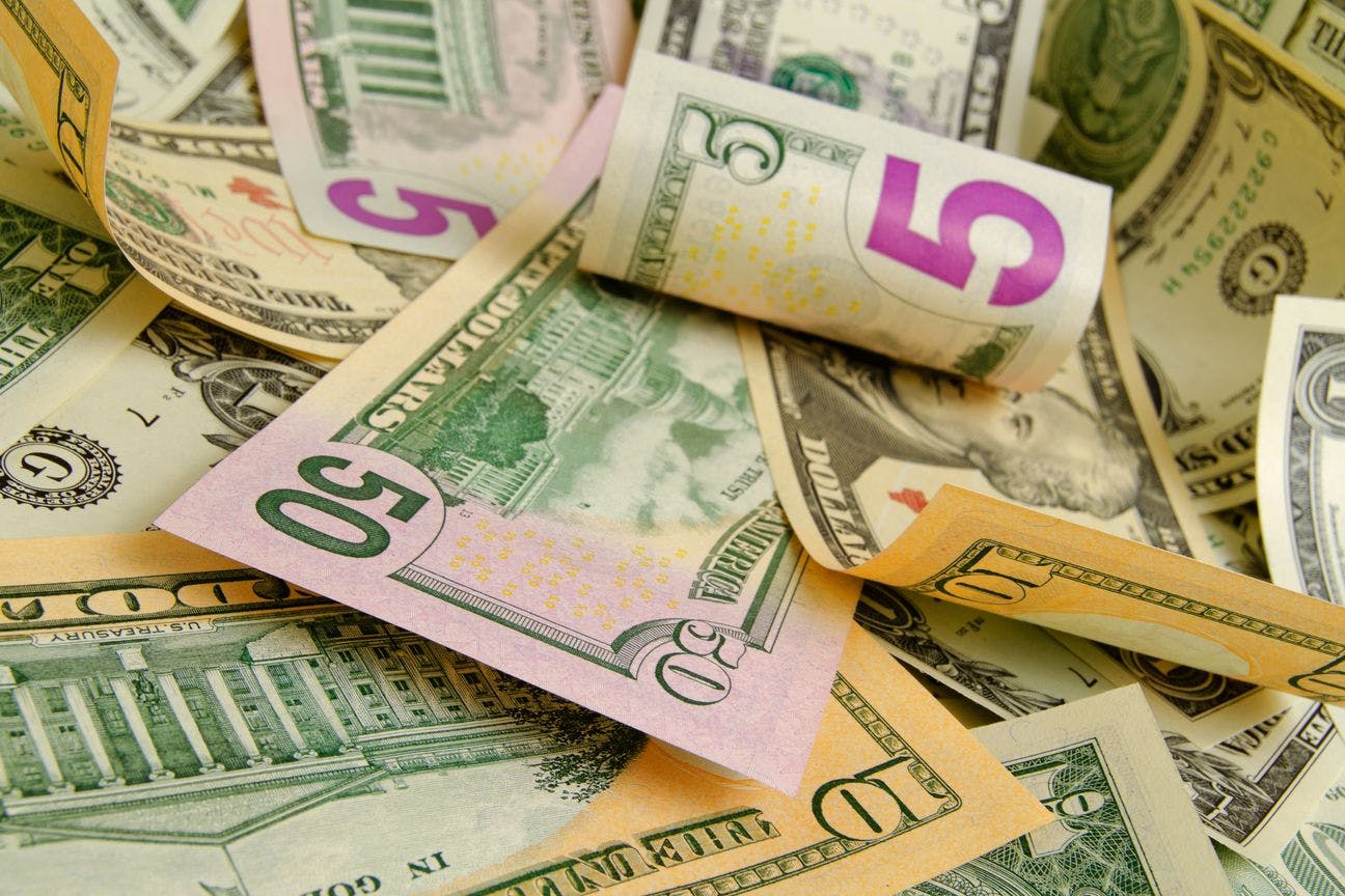 A pile of US cash, in denominations of $1, $5, $10 and $50 is strewn about. Cash is a difficult and dangerous piece of the cannabis industry.