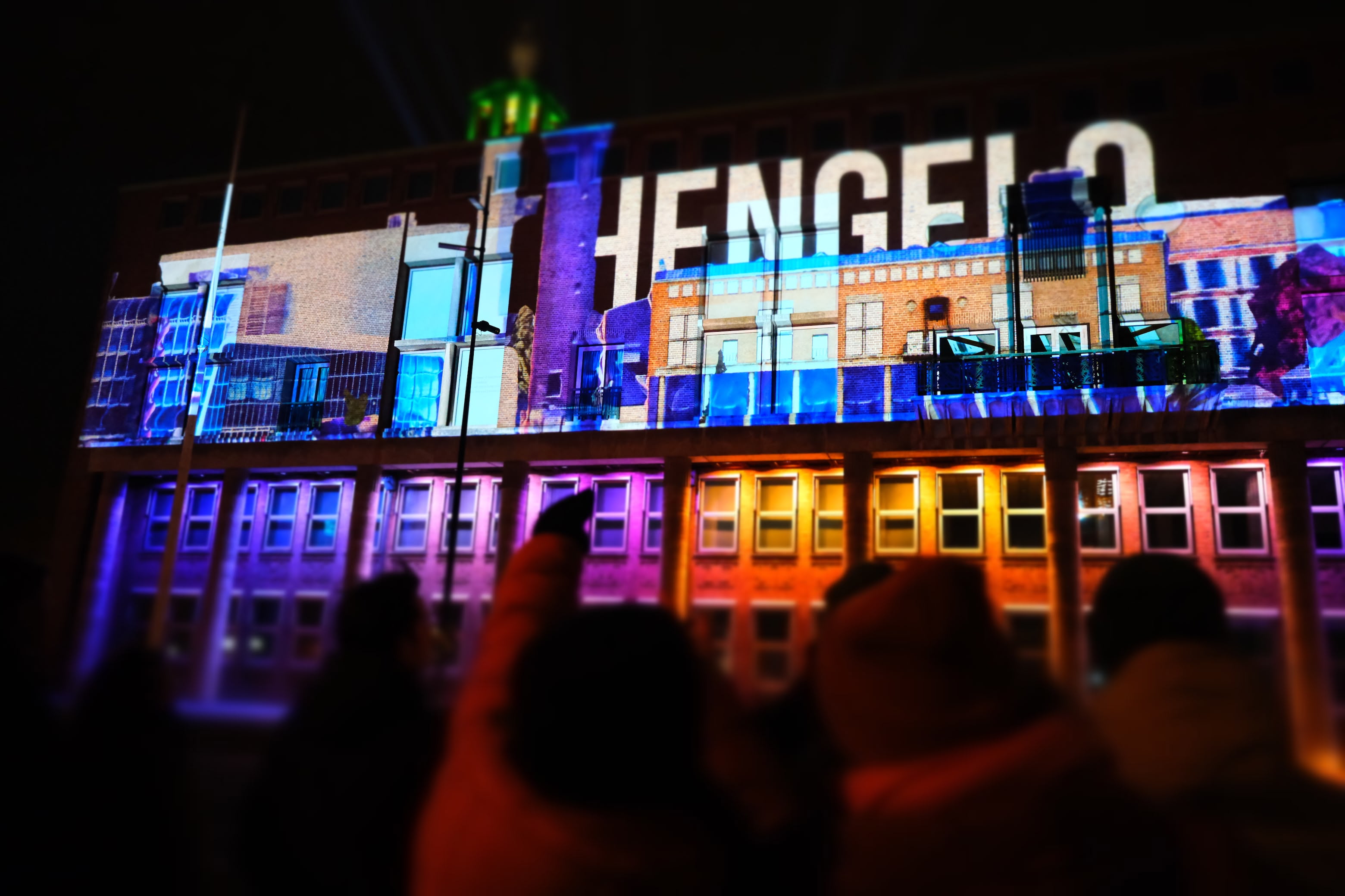 Mensen staan voor het stadhuis te kijken naar een projection mapping show in Hengelo