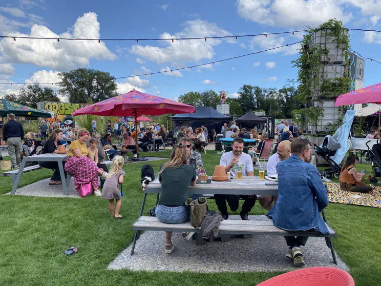Een groep mensen die op stoelen op een grasveld zitten onder een blauwe lucht