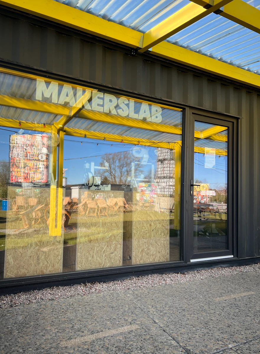 omgebouwde zeecontainer met glazen ruit waar de letters makerslab op staan