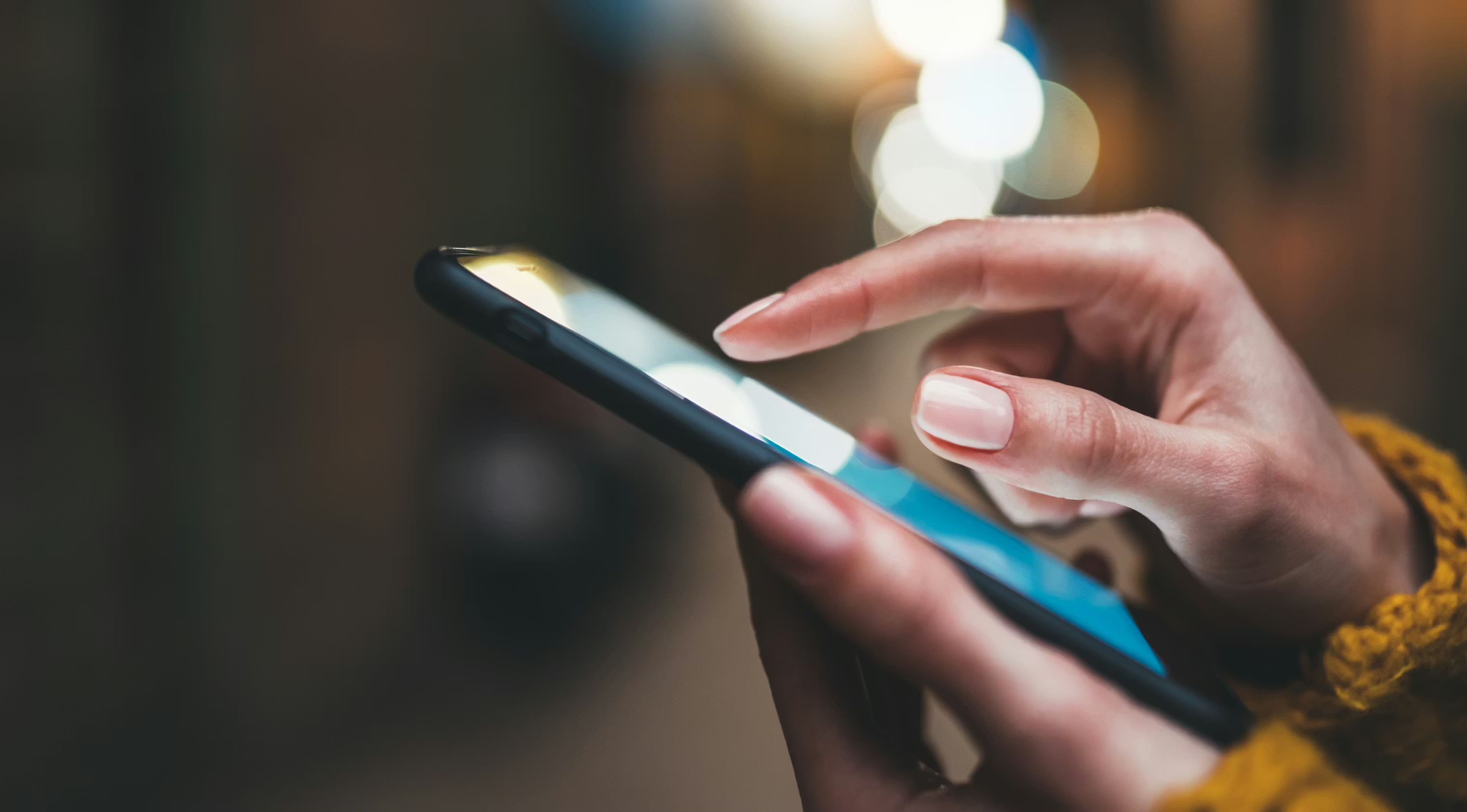 Close-up of person using smartphone touchscreen at night