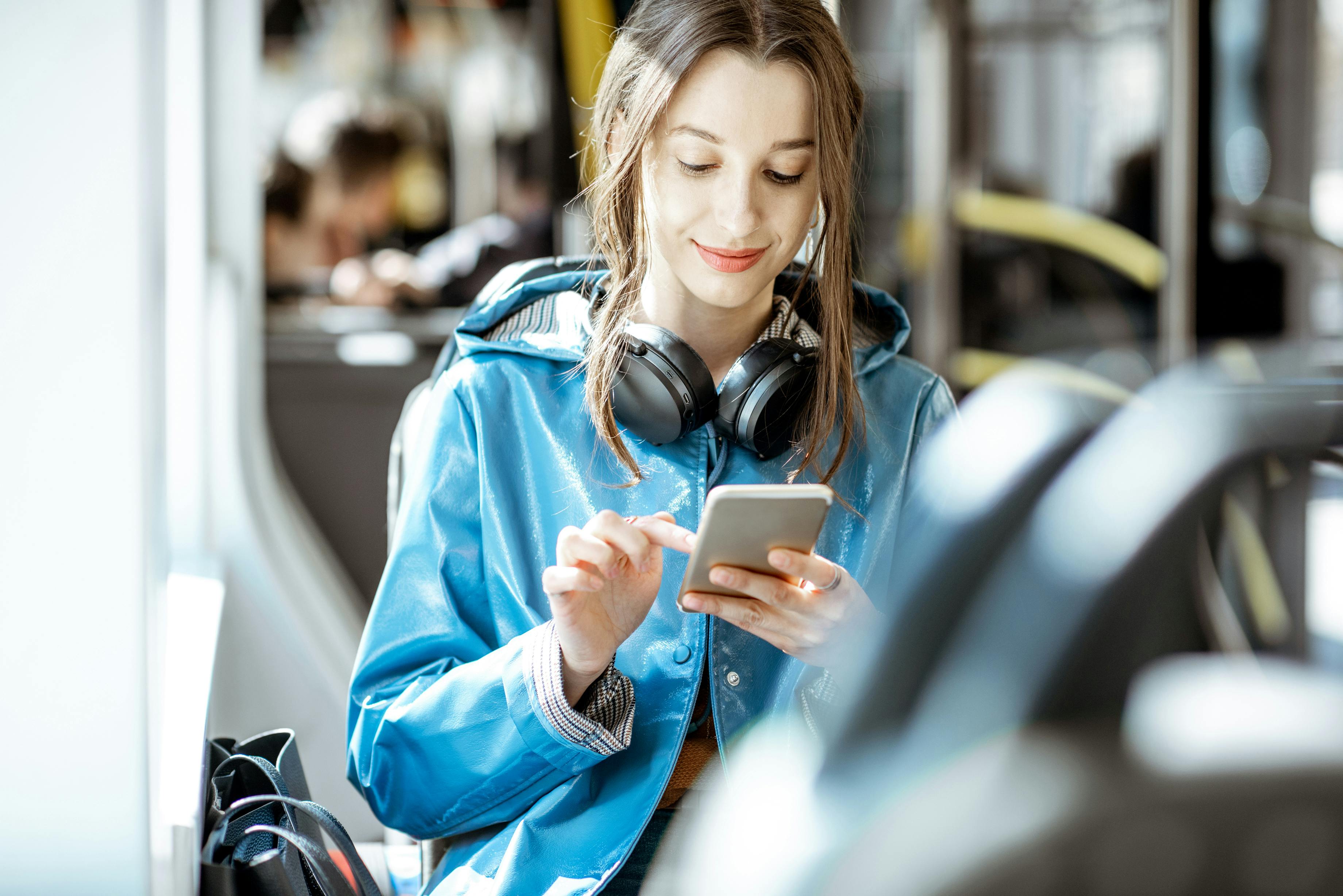 Woman using smartphone while riding public transit bus