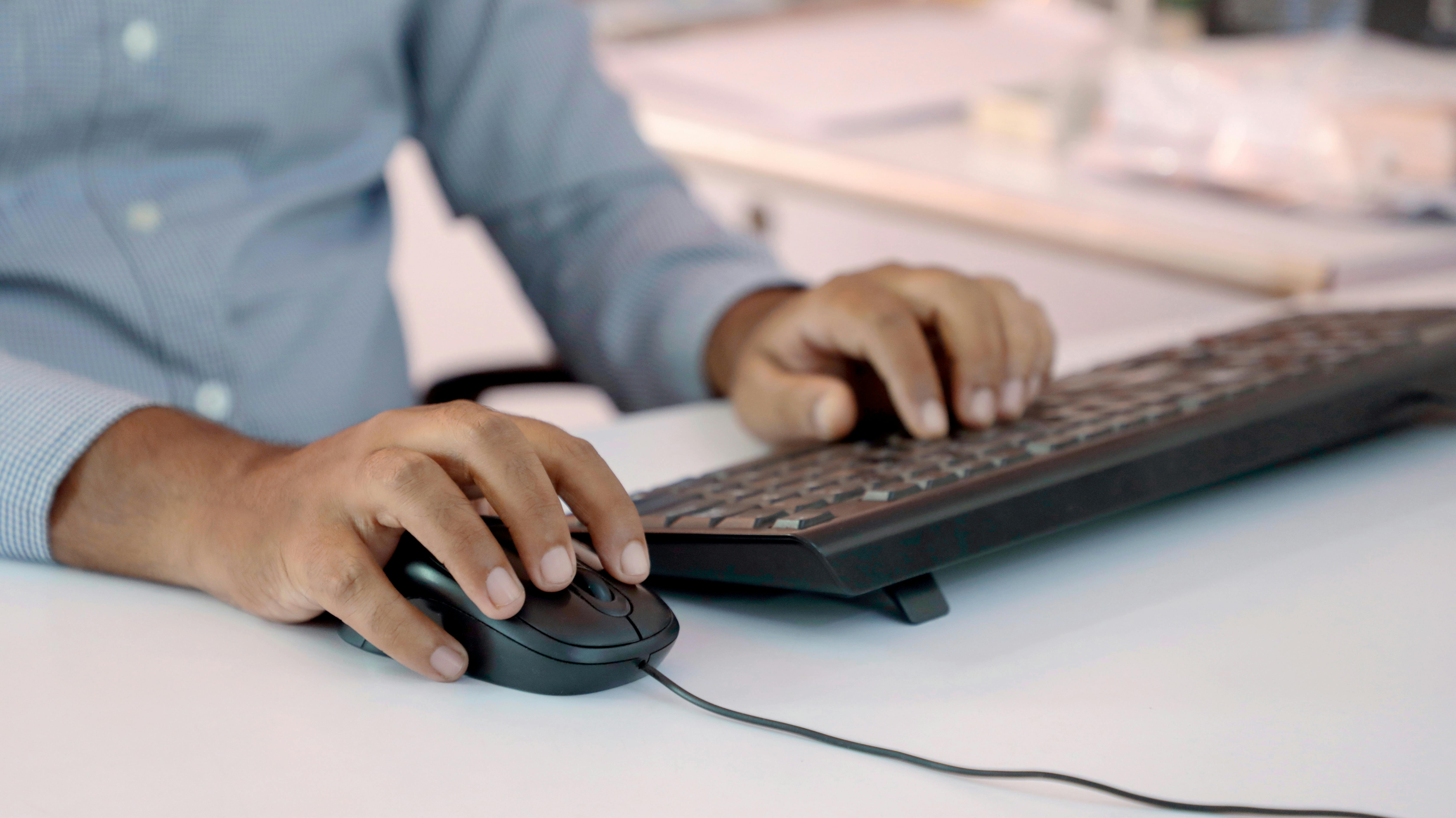 Person using computer keyboard and mouse in office setting