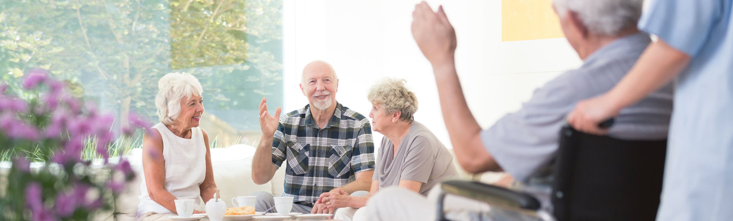 Group of seniors socializing in a senior living facility with caregiver support