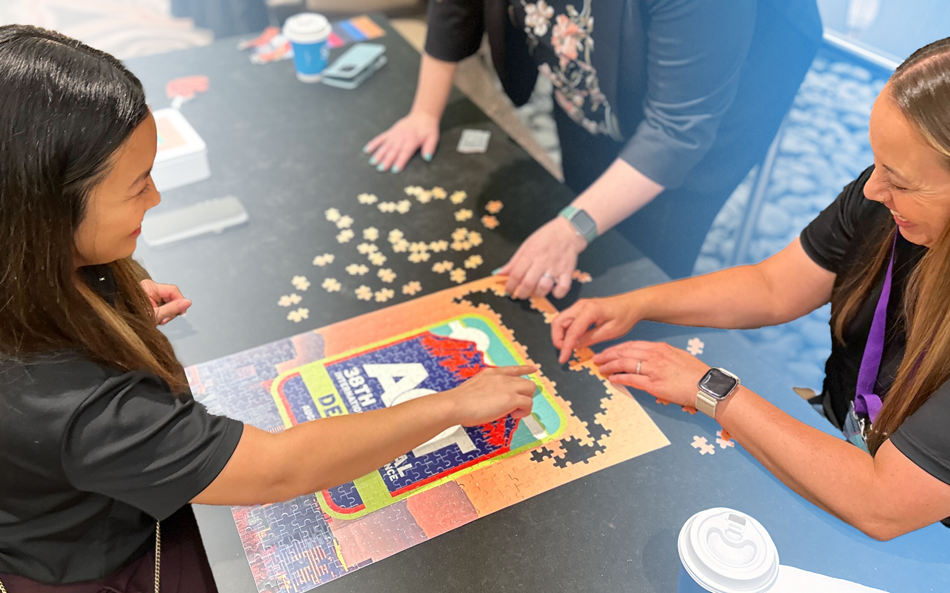 three women partaking in a puzzle-building activity at ACT International 2024 in Denver, Colorado.