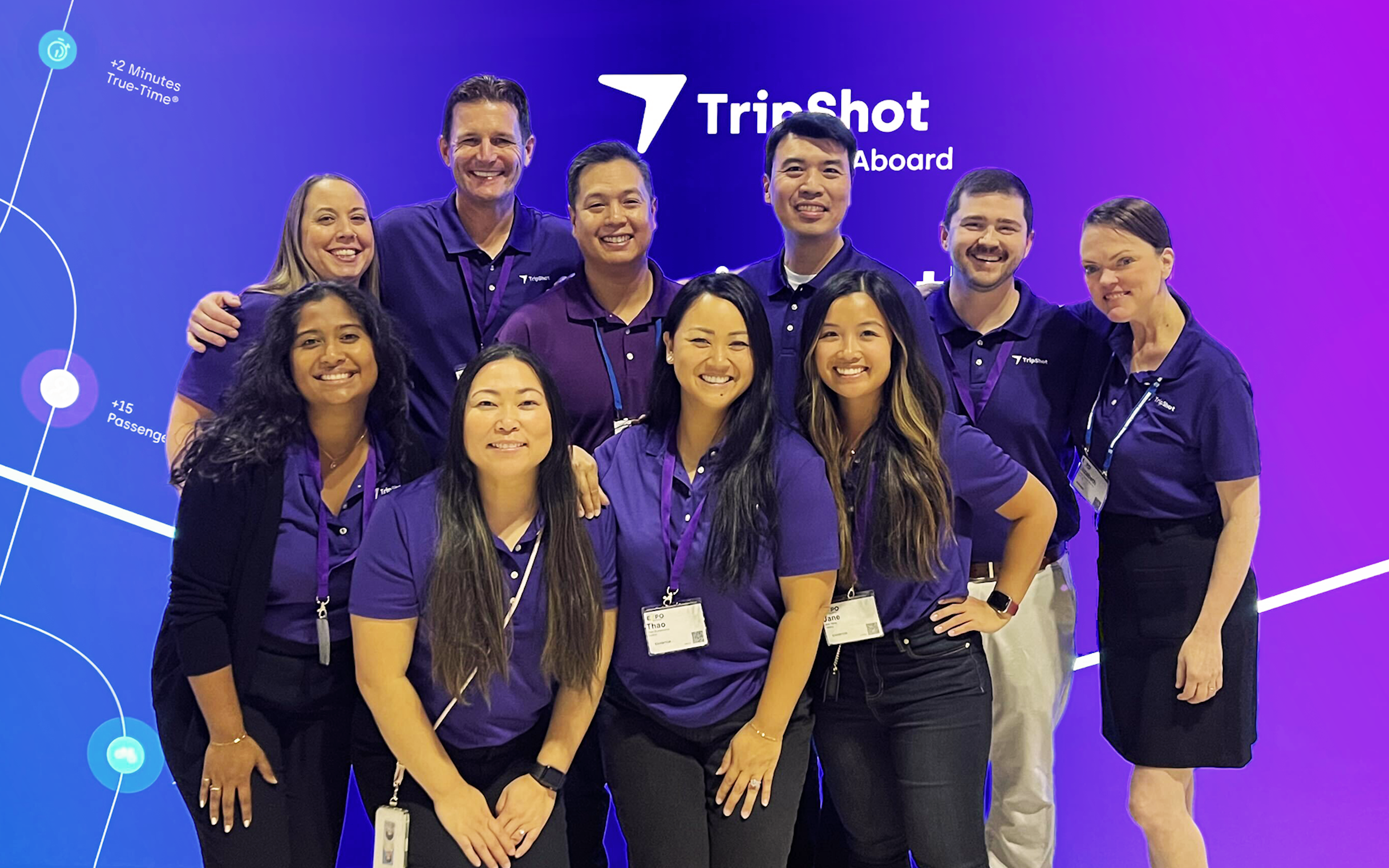 Group photo of TripShot employees in front of the light-up purple TripShot booth.
