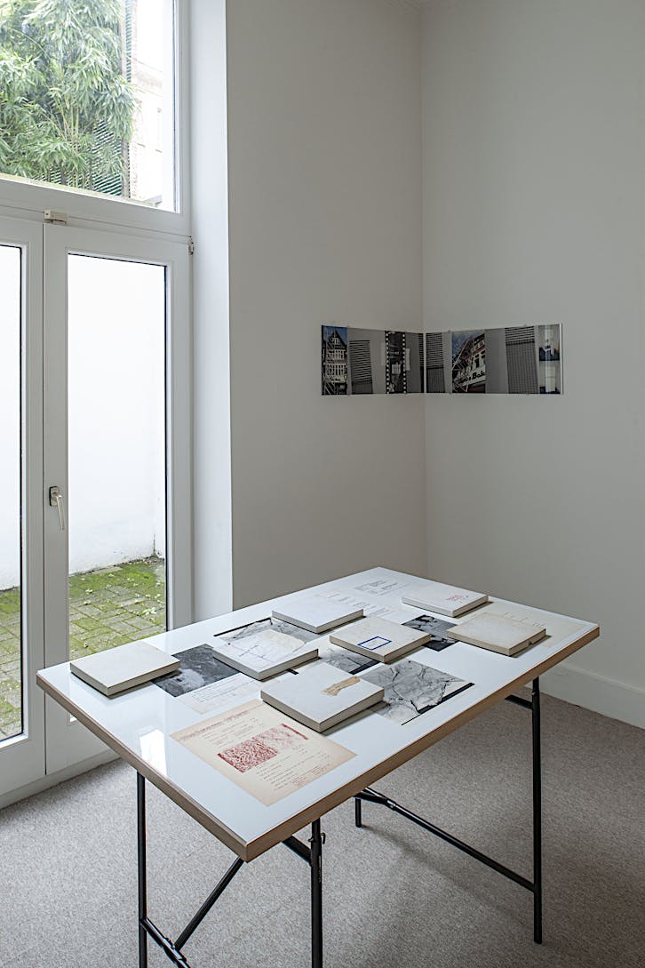 Vonna-Michell, Boxed Matter, 2022, table, plexiglass, printed matter from E.E. Vonna-Michell and Balsam Flex, 7 boxes with biodegradable elements, 120 x 80 cm (table), 18,3 x 18,3 cm (boxes, each); Tris Vonna-Michell, Broadway (after vonna-michell´s house by Henri Chopin, 1985), 2021, digital inkjet prints, diptych (each part: 32 cm x 76 cm). Installation view of Vonna-Michell: back segments at Jan Mot, Brussels, 2022, from front to back