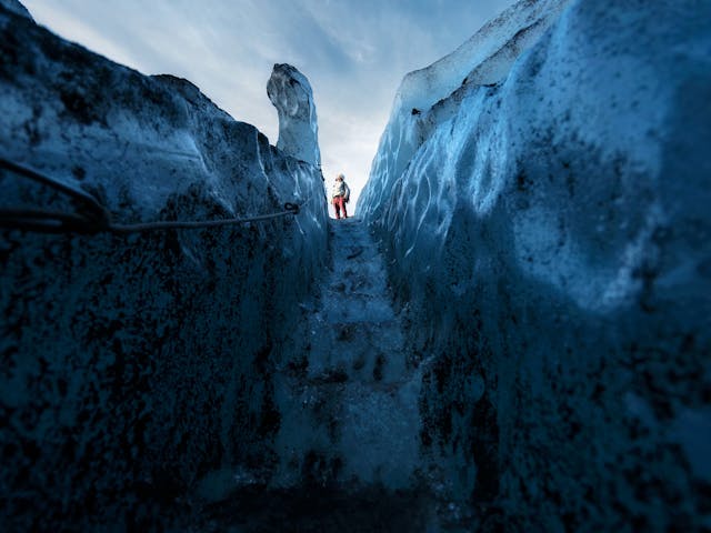 A man standing on top of the stairs that were carved out of the ice.
