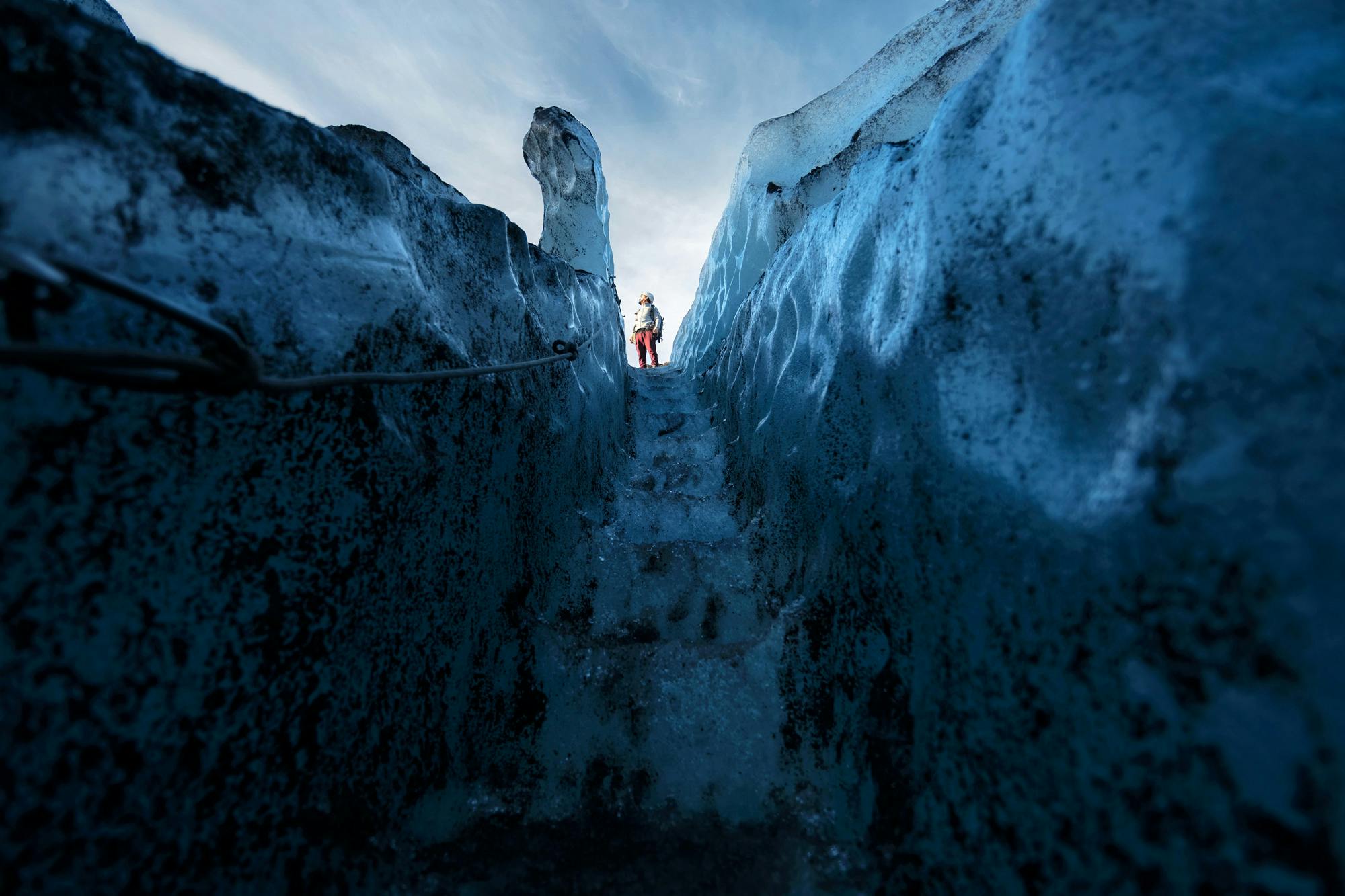 A man standing on top of the stairs that were carved out of the ice.