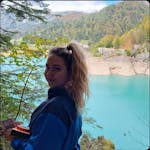 A blonde woman looking sideways with a lake and a forest in the background