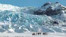 A group of people walking on a glacier plateau.