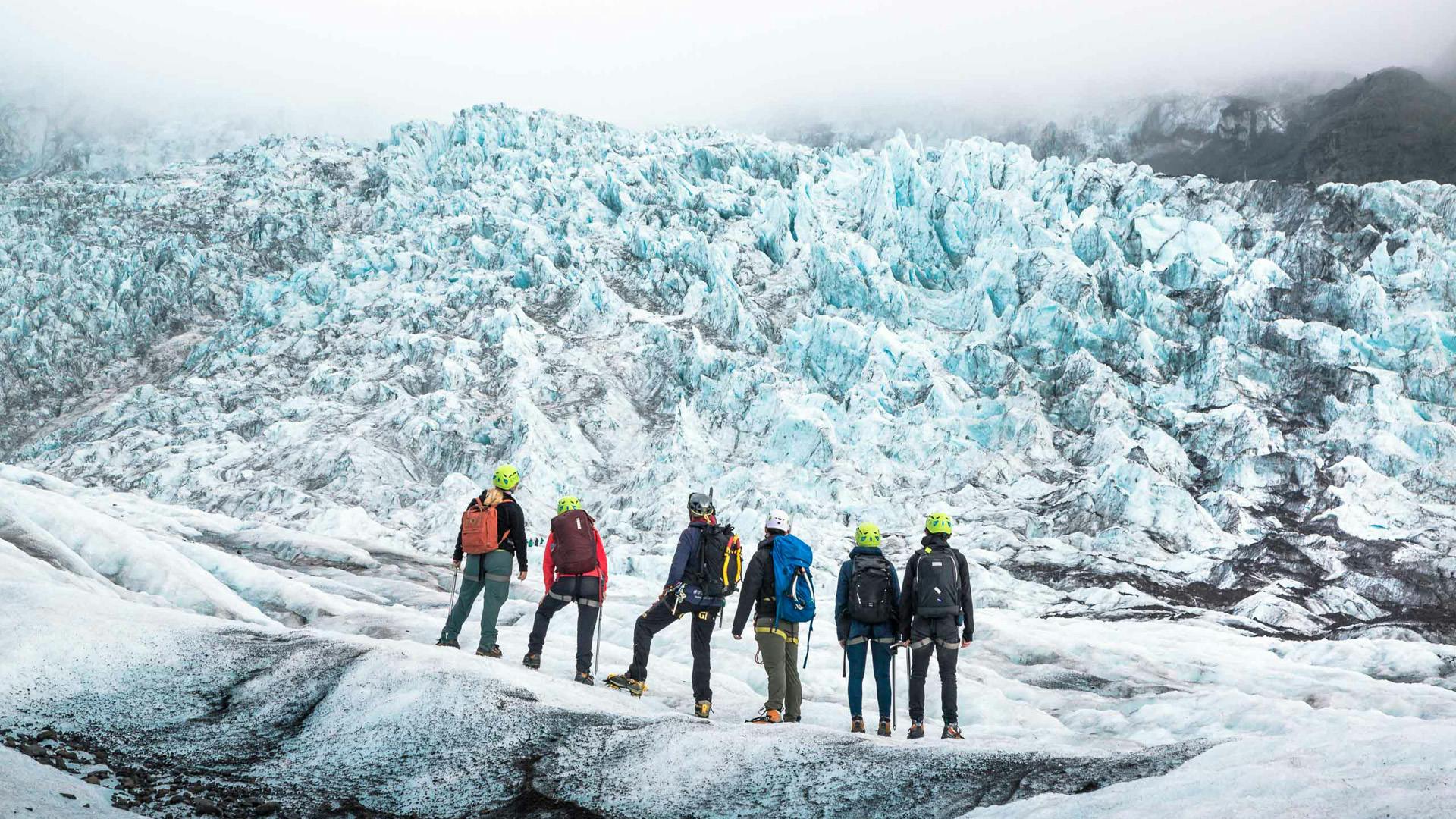 A group of people looking at the ice formations on a glacier.