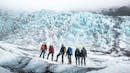 A group of people looking at the ice formations on a glacier.