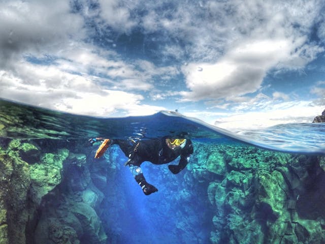 Photo taken with the waterline separating the underwater element from the surface element, with a person snorkeling in the center.