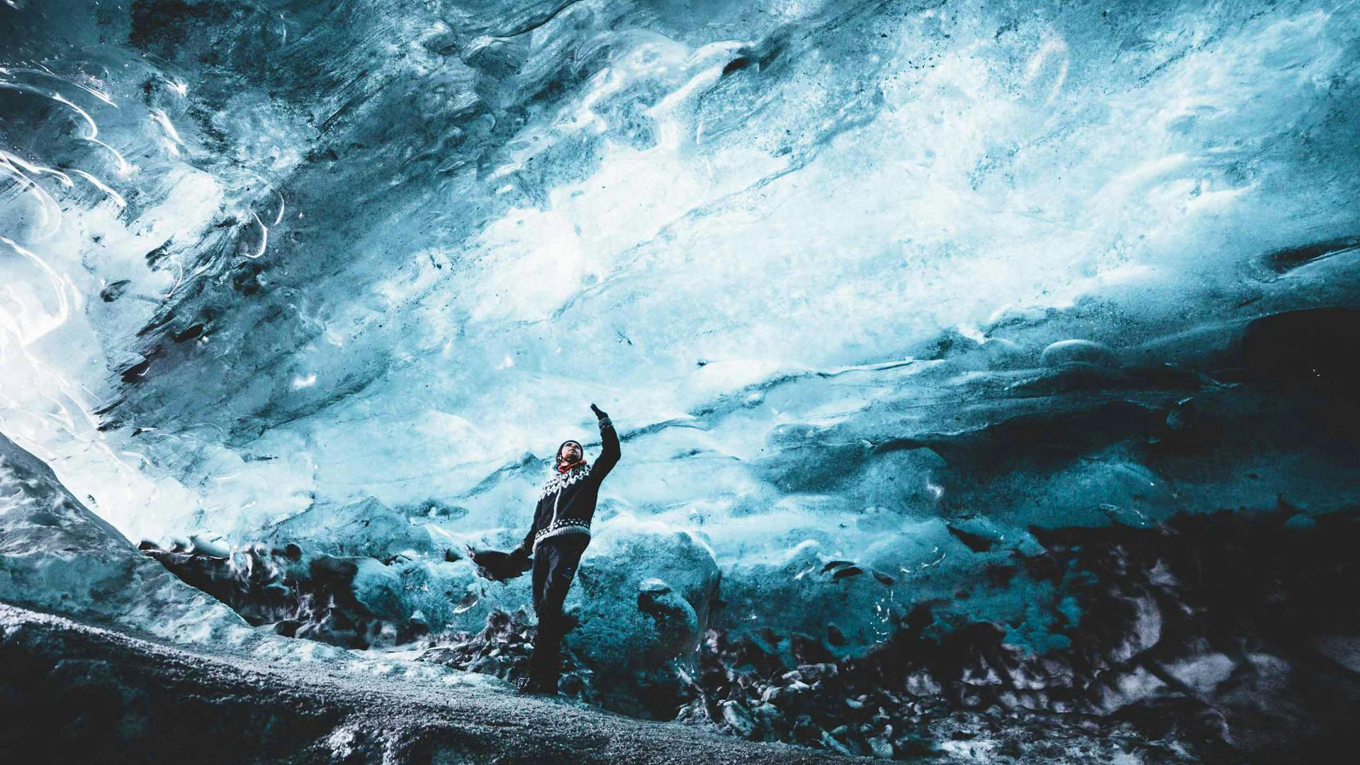 Person inside an ice cave, the person is touching on the ice cave ceiling.