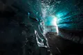 Person looking at the ceiling of an ice cave, the ice cave have layers of ashes inside from previous volcanic eruptions.