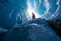 A person with a helmet enters an ice cave. 
