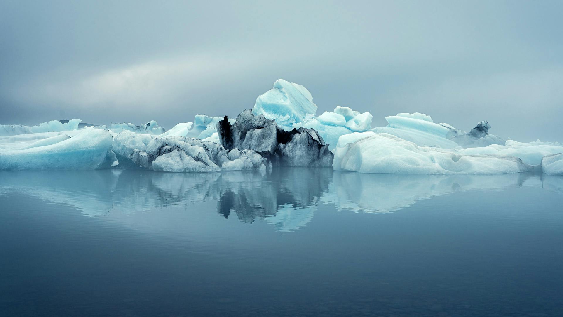 Glacial lagoon with floating icebergs creating a reflex in the calm water.