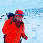 picture of a man using a red jacket and a red helmet with winter landscape in the background