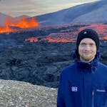 A man using a beanie with an active volcano on the background.