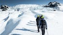 Group of people hiking on a glacier towards the ice falls.