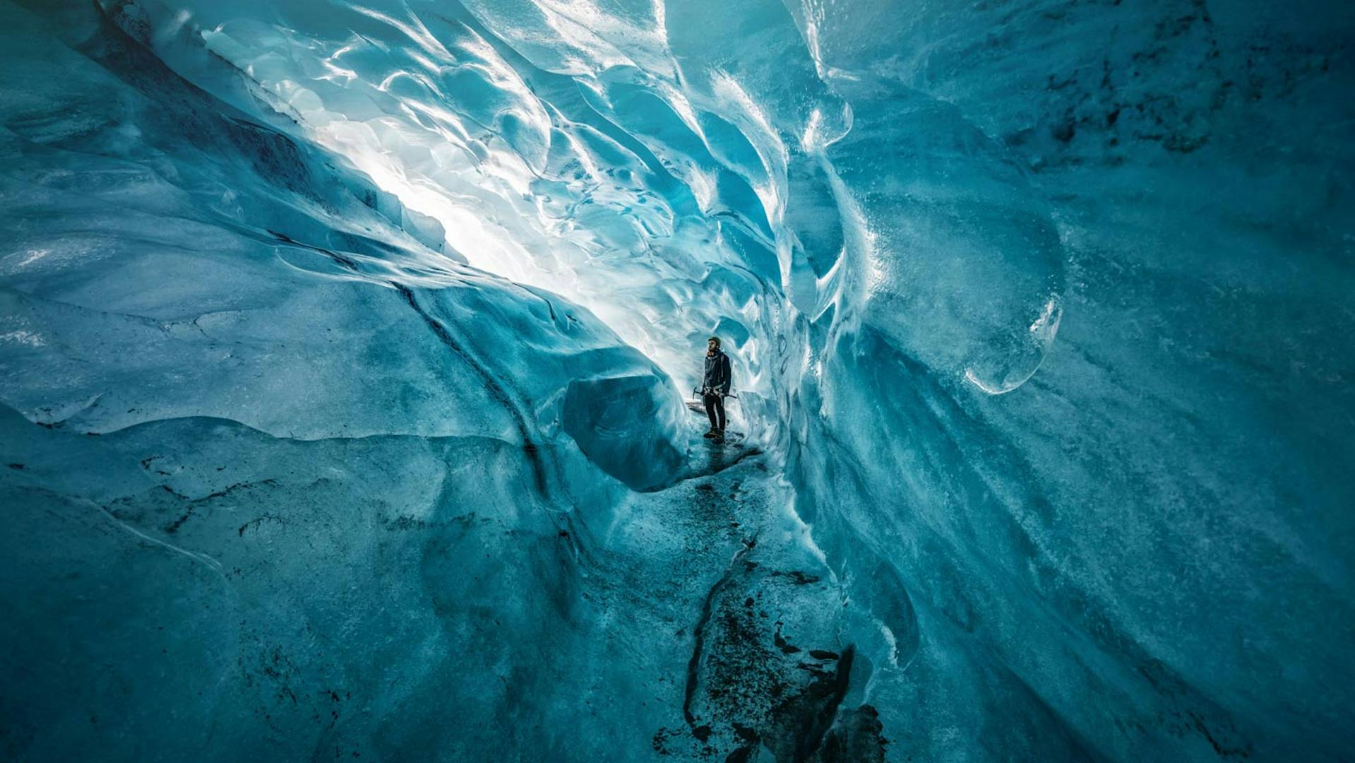 Person looking at the blue ice inside an ice cave.