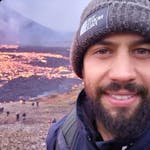 A face of a man with a volcano on the background.