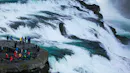People watching close a huge waterfall.