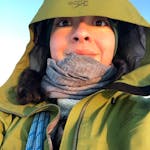 A woman using a green jacket with a hoodie.