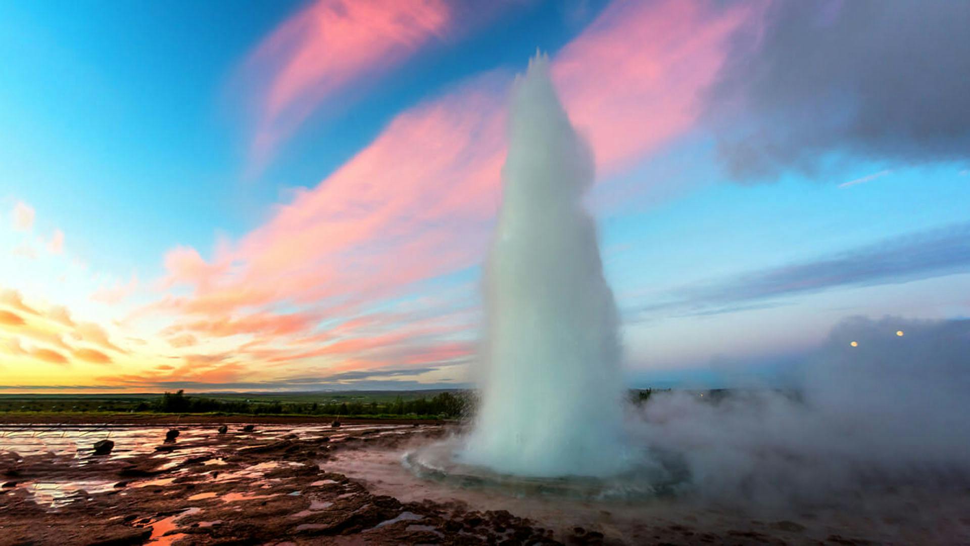 Geysir spew boiling water in the air during a sunset.