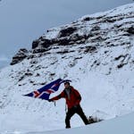 A man waving an Icelandic flag during winter time.