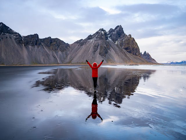 Woman standing on water in front of mountains