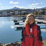 A woman wearing a red jacket and a life vest.