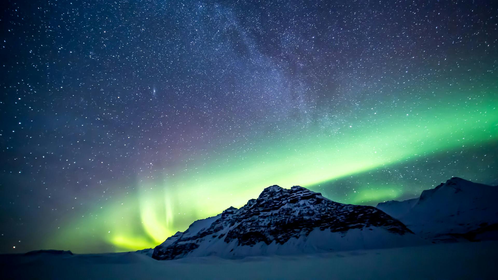 Mountain with a aurora borealis brightening up the sky.