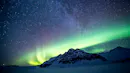 Mountain with a aurora borealis brightening up the sky.