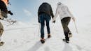 Couple holding hands and hiking on a glacier.