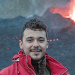 photo of a man using a red jacket with a volcano in the background