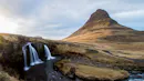 A waterfall on the left with a peaky mountain on the right.