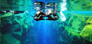 Man floating in Silfra Blue water while Snorkeling making a heart with his hands. 