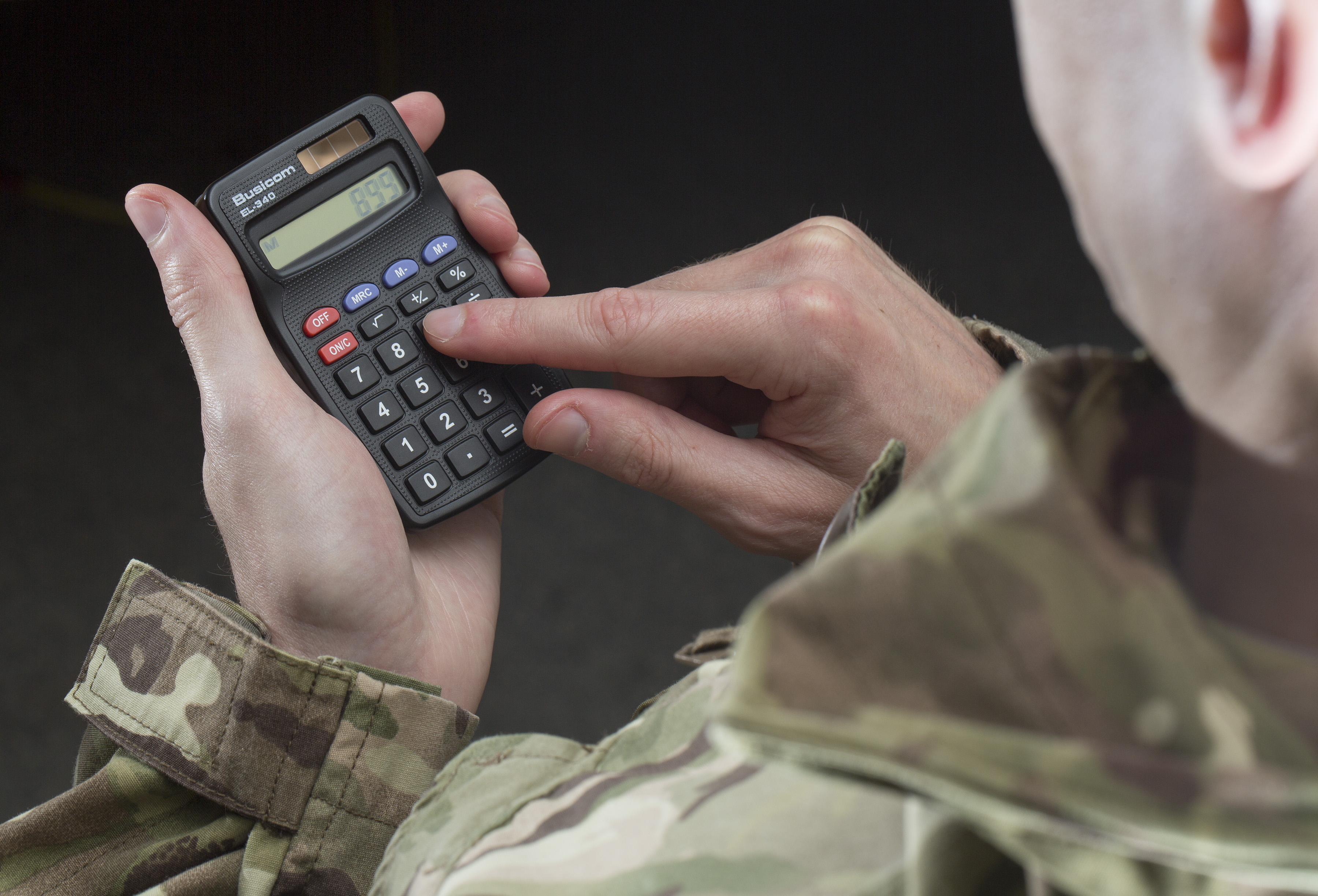military person in uniform using a calculator