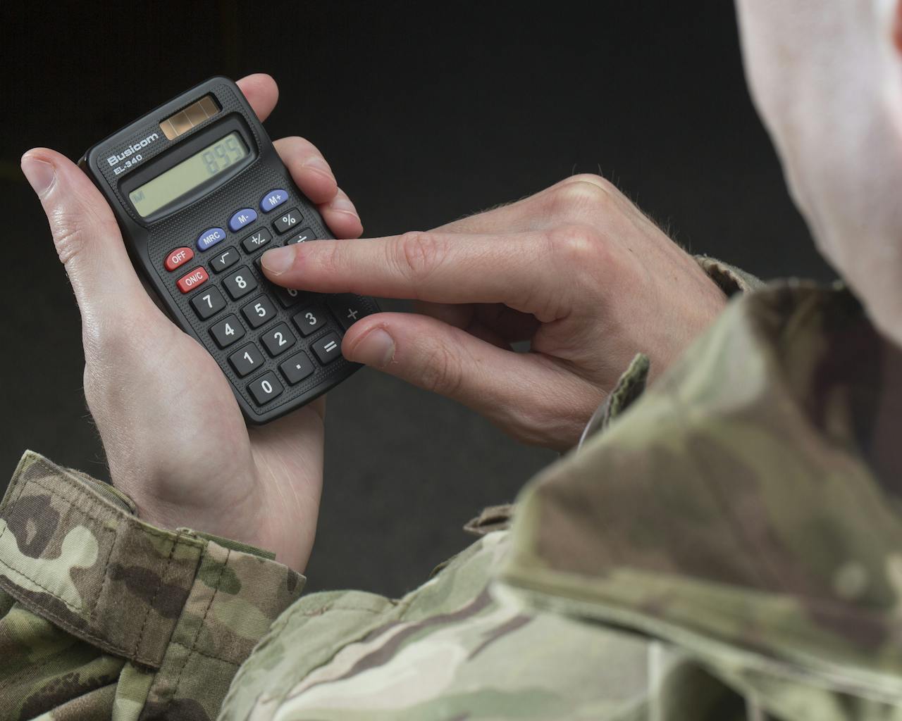 military person in uniform using a calculator