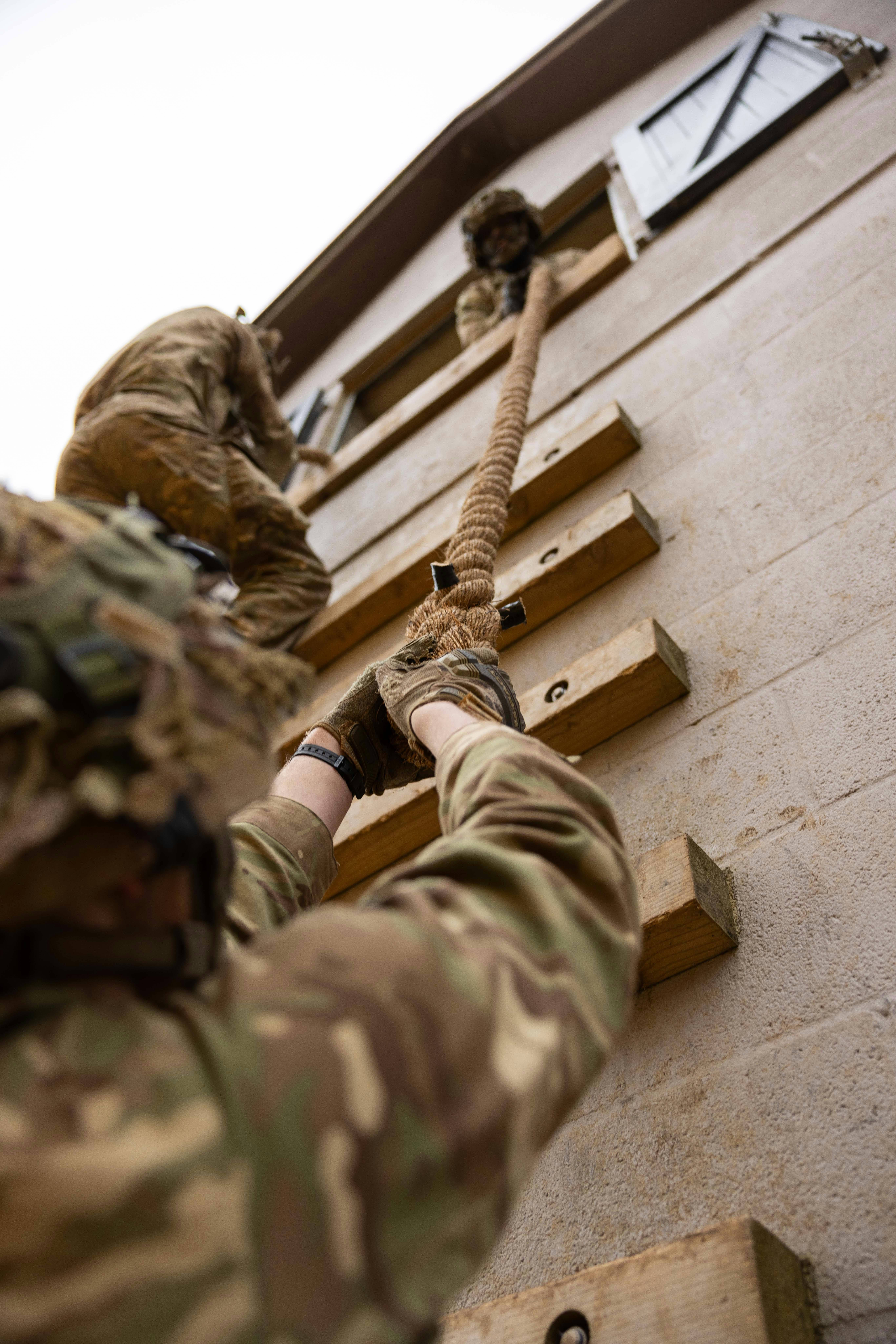 military person climbing a wall using a rope