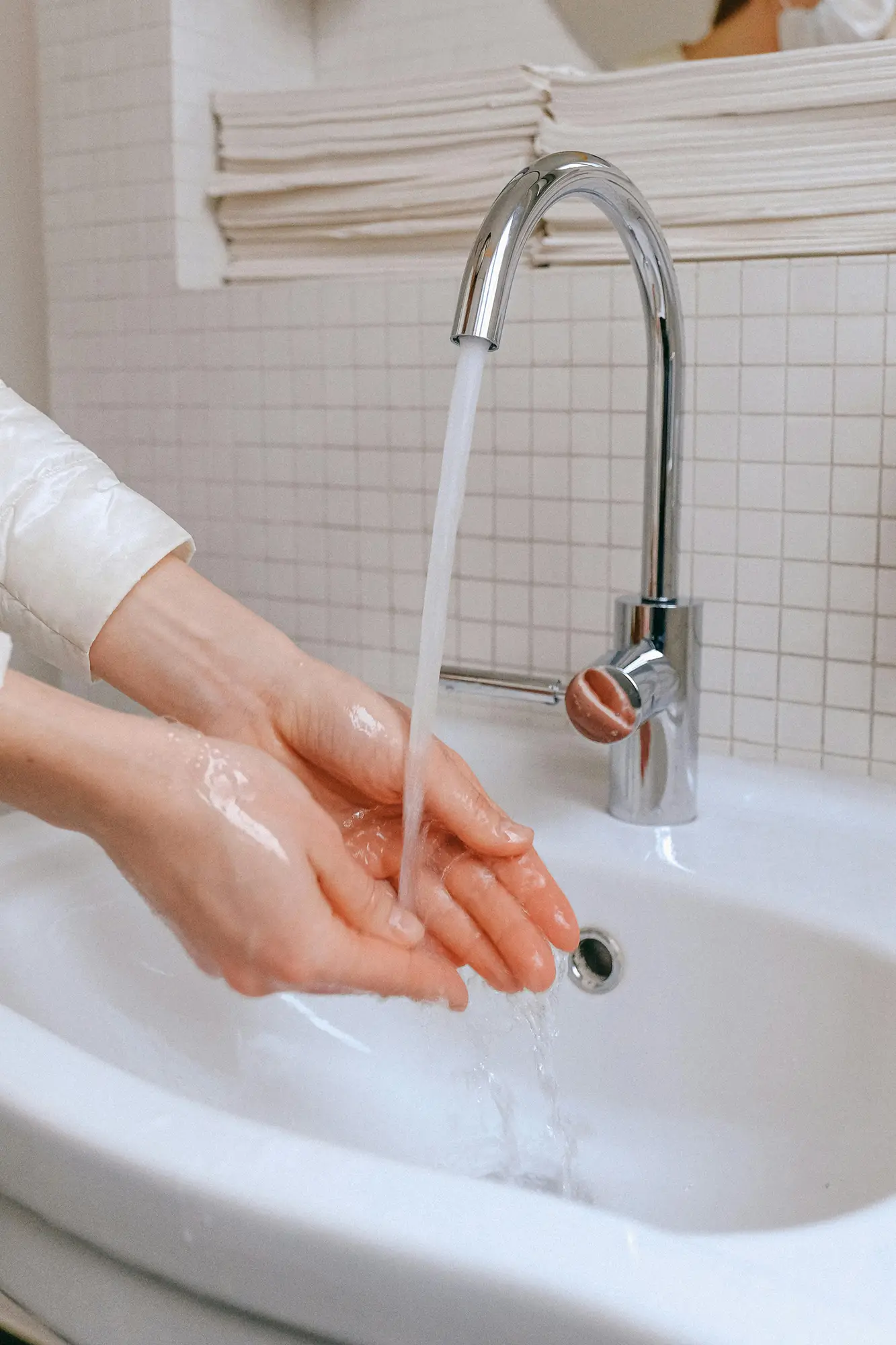 Closeup of washing hands in a white sink with silver-colored faucet
