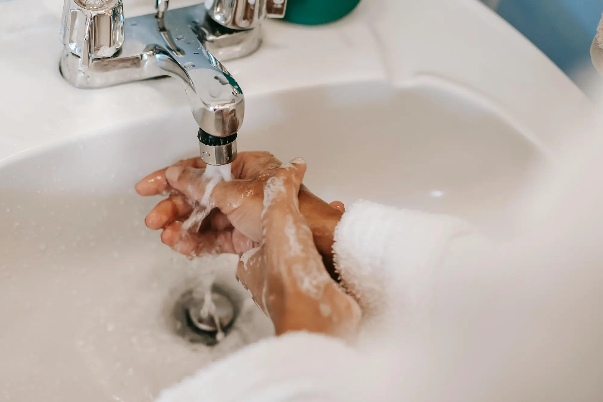 Person washing their soapy hands in a white sink