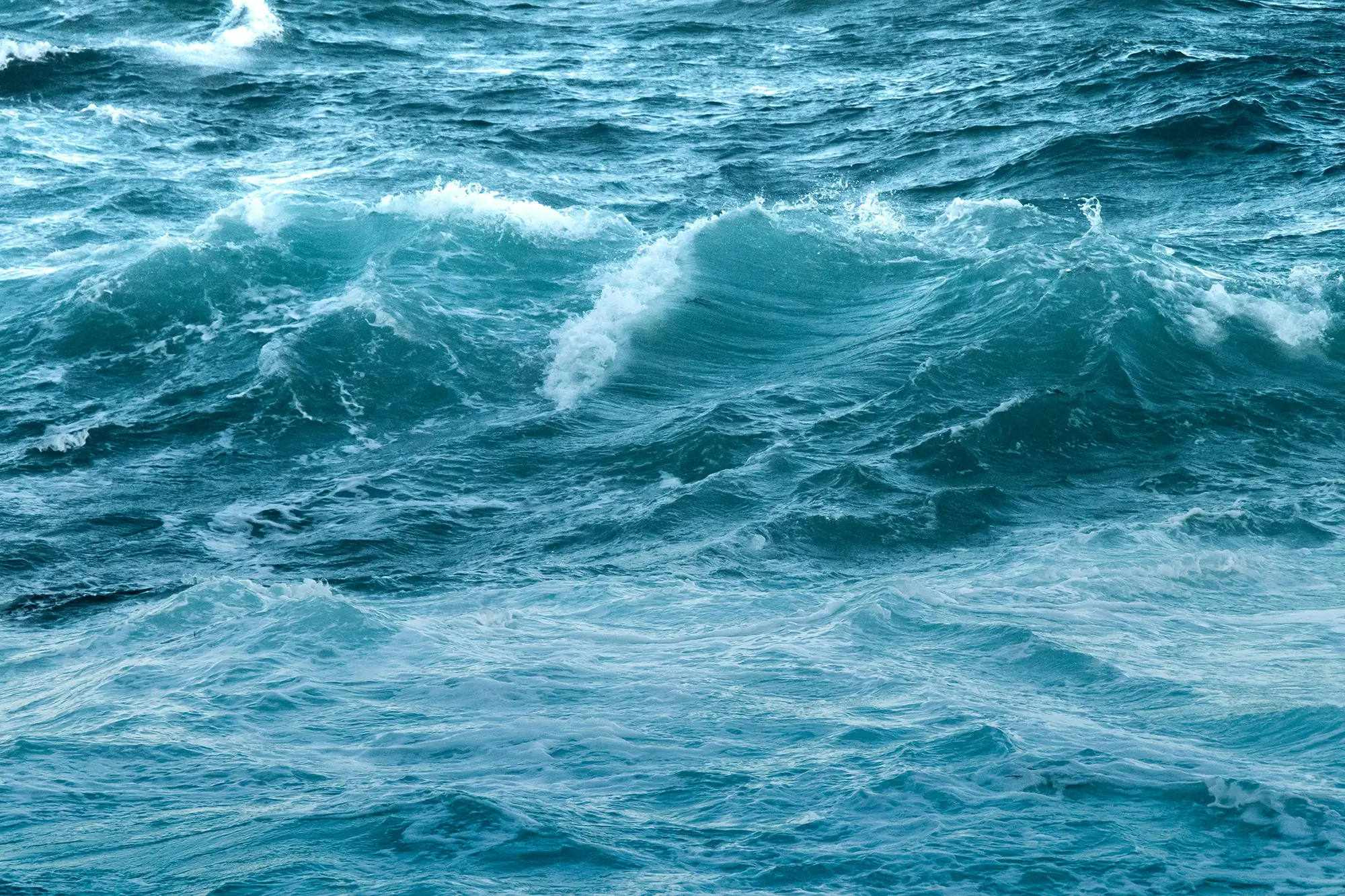 Blue ocean waves gently crashing against each other